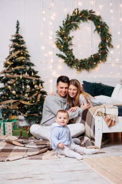 Noel ağacının yanında mutlu bir ailesi olan tatlı bir çocuk. Süslü bir Noel ağacının yakınındaki yatak odasında küçük bir çocuklu bir aile. Şenlikli yeni yıl atmosferi. Aile kutlaması