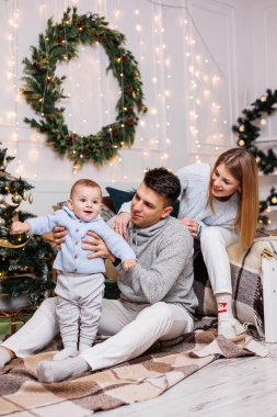 Noel ağacının yanında mutlu bir ailesi olan tatlı bir çocuk. Süslü bir Noel ağacının yakınındaki yatak odasında küçük bir çocuklu bir aile. Şenlikli yeni yıl atmosferi. Aile kutlaması