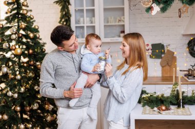Mutlu bir aile. Mutlu genç çift ve küçük oğulları yeni yıl süslemeleri için mutfakta. Yeni yıl içleri mutfakta. Noel mutfağı. Şenlikli aile ortamı.