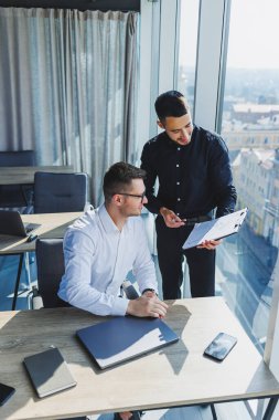 Modern bir yönetim kurulundaki toplantı sırasında iki iş adamı dizüstü bilgisayara bakarken bir proje hazırlıyorlar. Modern bir ofiste çalışma süreci