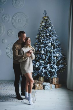 Birbirine aşık mutlu bir çift Noel ağacının yanında duruyor ve sarılıyorlar. Yeni yıl atmosferi. İki insanın Noel ağacının yanında şefkatle sarılıyorlar.