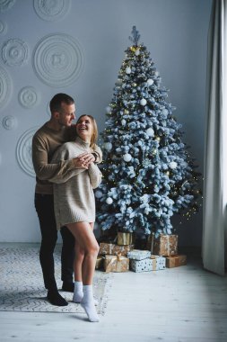 Birbirine aşık mutlu bir çift Noel ağacının yanında duruyor ve sarılıyorlar. Yeni yıl atmosferi. İki insanın Noel ağacının yanında şefkatle sarılıyorlar.