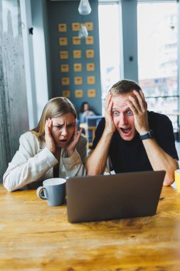 Genç iş arkadaşları masada oturuyor ve gülüyorlar. İş birliği ve takım çalışması kavramı. Ofisteki masada dizüstü bilgisayarla gülümseyen genç insanlar. Modern başarılı insanlar