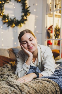 Gülümseyen bir kadının portresi yeni yıl süslemelerinin arka planında. Kadın Noel tatilinden memnun. Evde yeni yıl atmosferi