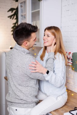Yeni yıl süslemeleri için mutfakta kucaklaşan mutlu genç çift. Yeni yıl içleri mutfakta. Noel mutfağı