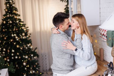 Yeni yıl süslemeleri için mutfakta kucaklaşan mutlu genç çift. Yeni yıl içleri mutfakta. Noel mutfağı