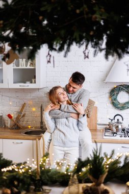 Yeni yıl süslemeleri için mutfakta kucaklaşan mutlu genç çift. Yeni yıl içleri mutfakta. Noel mutfağı