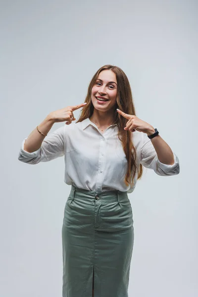 stock image a woman wears a white blouse and skirt on a gray background. emotions on a woman's face. Elegant look. positive woman. Model in casual clothes. Summer, spring or autumn street look.