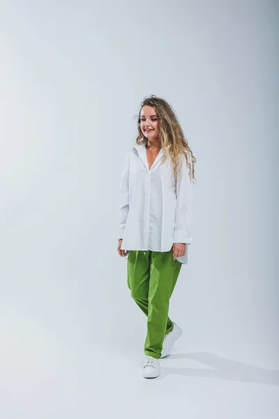 stock image Young curly woman in a white cotton shirt and pants on a white background. Female mole