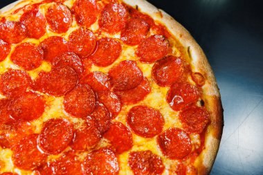 Sosisli dilimlenmiş pizza, domates sosu, mozzarella, soğan ve hamur kenarlı siyah arka planda krem peynirli.