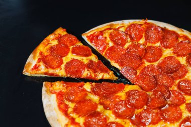 Sosisli dilimlenmiş pizza, domates sosu, mozzarella, soğan ve hamur kenarlı siyah arka planda krem peynirli.