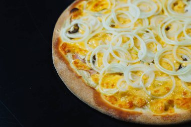 Soğan ve etle dilimlenmiş pizza, domates sosu, mozzarella, soğan ve hamurun kenarı, siyah arka planda krem peynirle dolu.