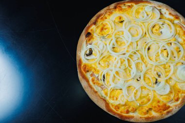 Soğan ve etle dilimlenmiş pizza, domates sosu, mozzarella, soğan ve hamurun kenarı, siyah arka planda krem peynirle dolu.