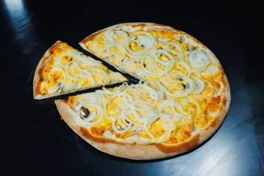 Soğan ve etle dilimlenmiş pizza, domates sosu, mozzarella, soğan ve hamurun kenarı, siyah arka planda krem peynirle dolu.