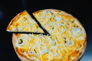 Soğan ve etle dilimlenmiş pizza, domates sosu, mozzarella, soğan ve hamurun kenarı, siyah arka planda krem peynirle dolu.