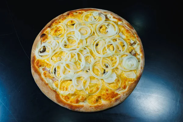 Sliced pizza with onion and meat, tomato sauce, mozzarella, onion and edge of dough, filled with cream cheese on a black background