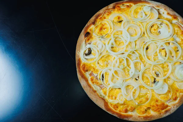 Sliced pizza with onion and meat, tomato sauce, mozzarella, onion and edge of dough, filled with cream cheese on a black background
