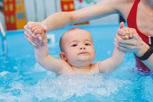 stock image A swimming teacher teaches a little boy to swim in the pool. Children's first swimming lessons. Development for babies