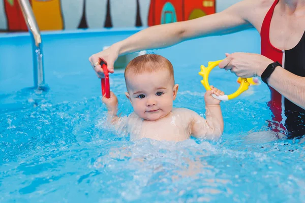 stock image A beautiful mother teaches teaches her little son how to swim in the pool. A child is having fun in the water with his mother. Child development. First swimming lessons for children