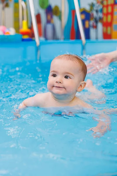Swimming lessons for children. A little boy is learning to swim in a baby pool. Children's development. First swimming lessons for children