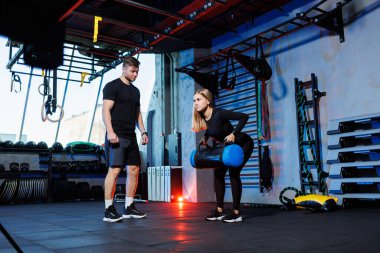 Spor, fitness, vücut geliştirme, yaşam tarzı ve konseptler. Spor salonunda spor yapan bir kadının katı rehberliği altında spor yapan bir kadın. Spor salonunda kasları çalıştırıyor.