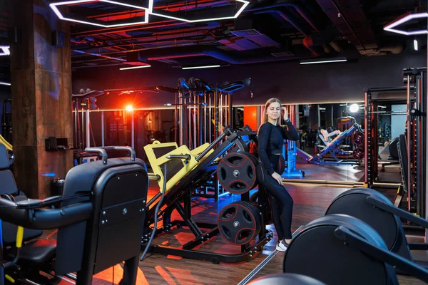 stock image A young woman in black leggings does sports in a modern gym