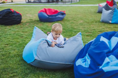 Aleti olan modern bir çocuk. Güneşli bir günde küçük bir çocuk dışarıda oturuyor ve telefonda oyun oynuyor..