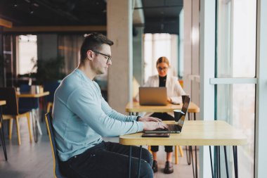 Başarılı iş adamı lideri, gelecekteki kurumsal başarı planlarını düşünüyor, ofis masasında dizüstü bilgisayarla oturuyor, modern şirket inşaatının panoramik penceresine bakıyor..