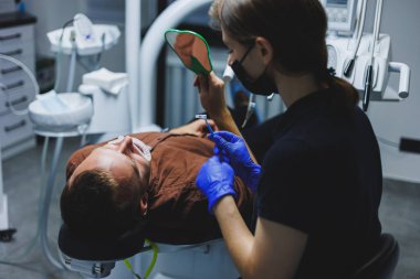 Dişlerin ortodontik tedavisi. Doktor hastanın dişlerine metal diş telleri takıyor. Ağız bakımı. Seçici odak