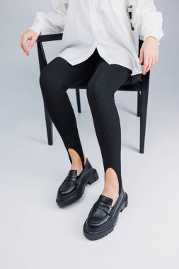 Siyah deri ayakkabılar ve siyah taytlar içinde güzel kadın bacakları. Yaz kadın ayakkabıları.