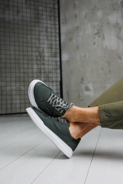 Pantolon giymiş erkek bacakları ve yeşil spor ayakkabıları. Erkek ayakkabıları.