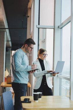 İş adamları kahve içerken iş konuşuyorlar laptopa, modern çalışma alanına bakıyorlar. İş arkadaşları ofiste birlikte çalışırlar.