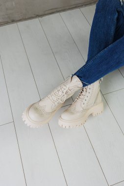 Kotlu kadın bacakları ve doğal deriden yapılmış beyaz deri çizmeler. Bir kadın bahar modern ayakkabısı koleksiyonu.