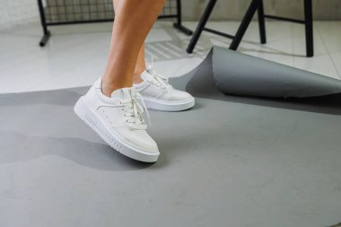 Genç, deri ayakkabılı, beyaz arka planda duran güzel bir kadın. Şık ayakkabılı kadın bacakları. Sıradan beyaz kadın ayakkabıları.