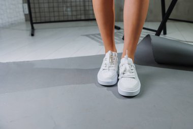 Genç, deri ayakkabılı, beyaz arka planda duran güzel bir kadın. Şık ayakkabılı kadın bacakları. Sıradan beyaz kadın ayakkabıları.