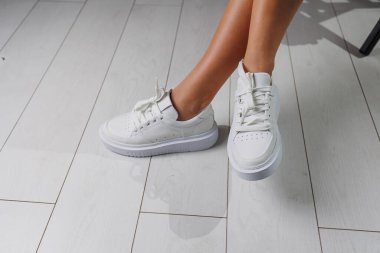 Beyaz klasik spor ayakkabılar içinde mükemmel kadın bacakları. Beyaz ayakkabılar içinde güzel kadın bacakları.