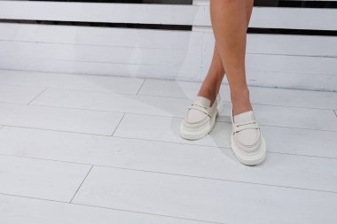 Beyaz deri ayakkabılar içindeki güzel kadın bacakları. Yaz kadın ayakkabıları.