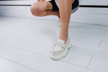 Beyaz deri ayakkabılar içindeki güzel kadın bacakları. Yaz kadın ayakkabıları.