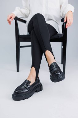 Siyah deri ayakkabılar ve siyah taytlar içinde güzel kadın bacakları. Yaz kadın ayakkabıları.