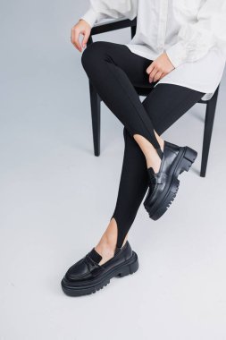 Siyah deri ayakkabılar ve siyah taytlar içinde güzel kadın bacakları. Yaz kadın ayakkabıları.