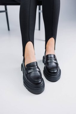 Siyah deri ayakkabılar ve siyah taytlar içinde güzel kadın bacakları. Yaz kadın ayakkabıları.