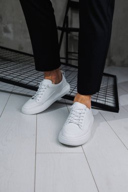 Erkek bacakları yakın plan. Şık siyah pantolonlu ve beyaz deri ayakkabılı bir adam. Günlük bakışın ayrıntıları. Erkekler sokak modası