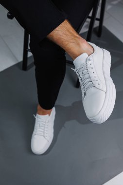 Modern erkek ayakkabıları. Siyah pantolonlu ve beyaz spor ayakkabılı erkek bacakları. Erkek ayakkabıları.