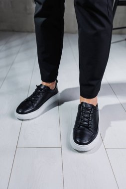 Modern erkek ayakkabıları. Siyah pantolonlu ve siyah spor ayakkabılı erkek bacakları. Erkek ayakkabıları.