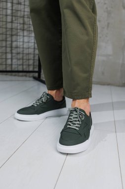 Pantolon giymiş erkek bacakları ve yeşil spor ayakkabıları. Erkek ayakkabıları.