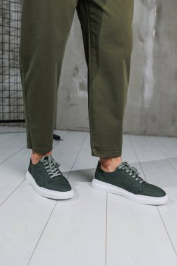 Pantolon giymiş erkek bacakları ve yeşil spor ayakkabıları. Erkek ayakkabıları.