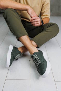 Pantolon giymiş erkek bacakları ve yeşil spor ayakkabıları. Erkek ayakkabıları.