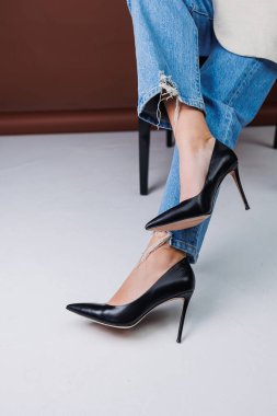 Kot pantolon ve siyah deri topuklular içinde güzel kadın bacakları. Kadın kış ayakkabıları.