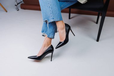 Kot pantolon ve siyah deri topuklular içinde güzel kadın bacakları. Kadın kış ayakkabıları.