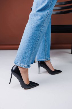 Kot pantolon ve siyah deri topuklular içinde güzel kadın bacakları. Kadın kış ayakkabıları.